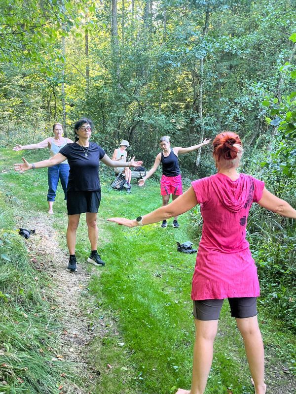 4 Frauen praktizieren Wyda im Wald (stehen in Grätsche mit ausgebreiteten Armen)
