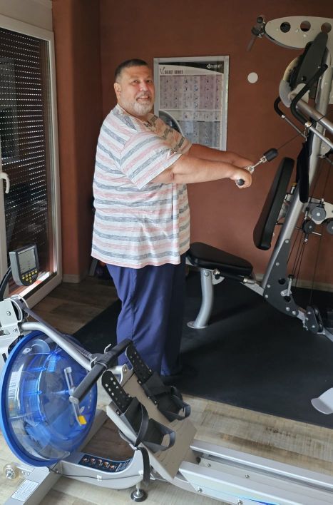 Gut genährter Mann stehend bei einem Fitnessgerät