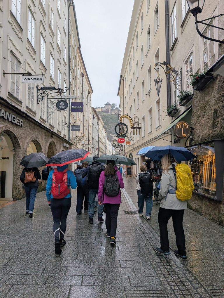 Drei Teilnehmerinnen von hinten mit Regenschirm in der Salzburger Getreidegasse