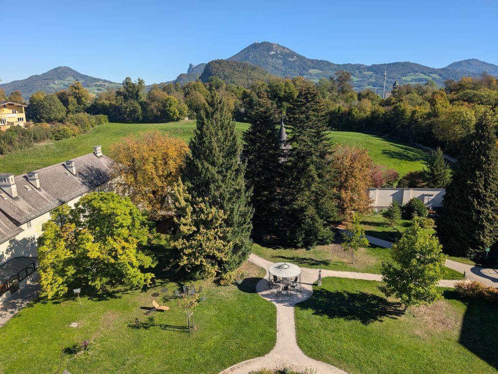 Blick in einen grünen Innenhof - im Hintergrund Wiesen und Berge